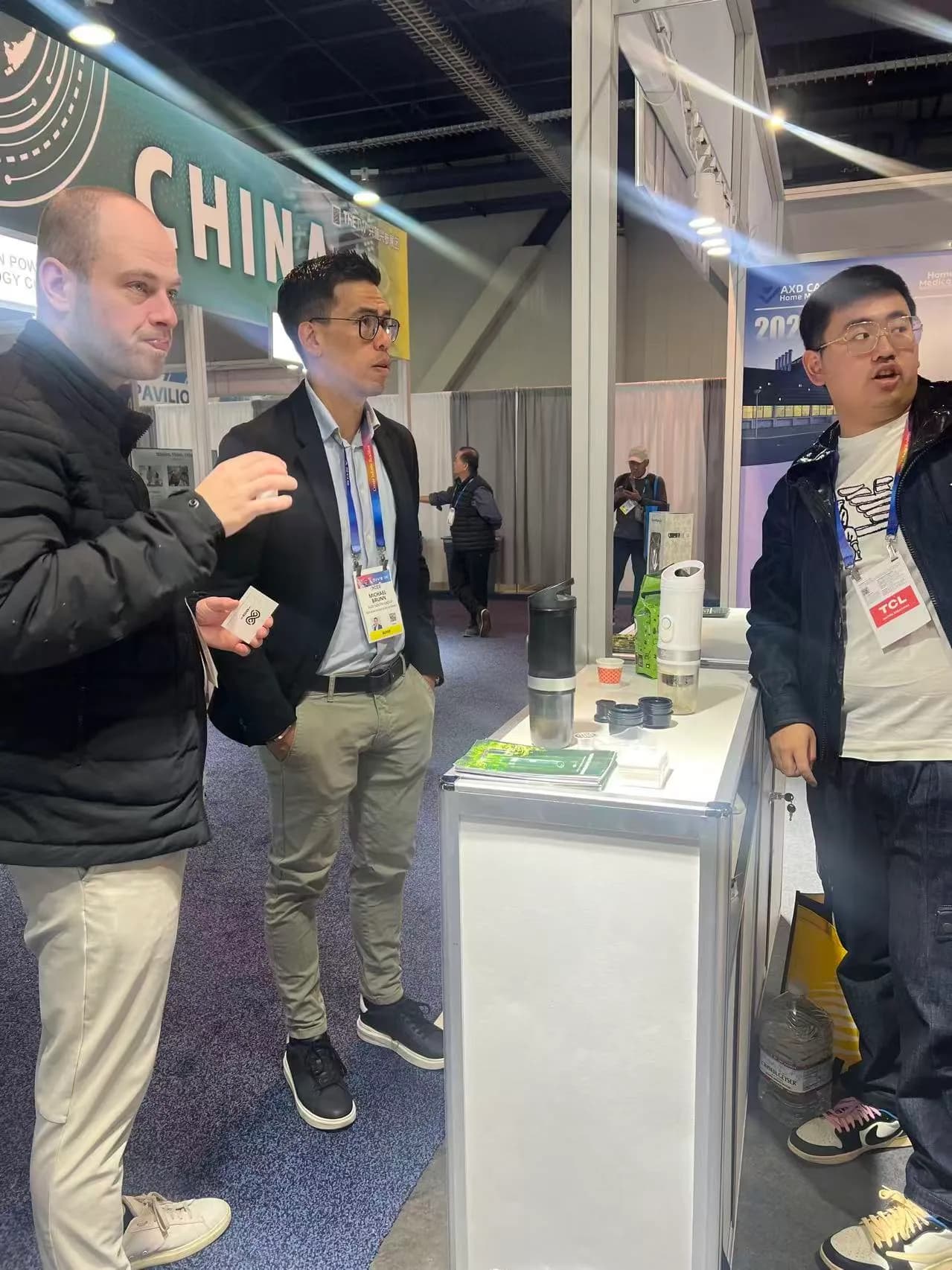 Visitors discussing portable coffee products at an international exhibition booth
