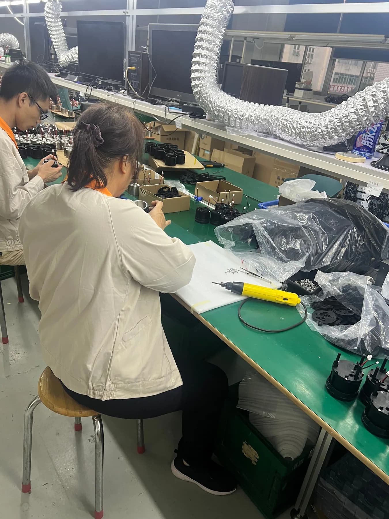 Operators assembling portable coffee machine components on the production line